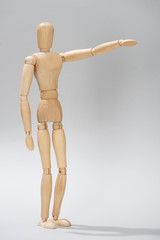 Wooden doll with outstretched hand on grey background