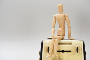 Wooden doll on vintage radio isolated on grey