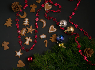 Christmas ginger cookies with white, sweet icing in the shape of Christmas trees, stars, angels and hearts on a dark concrete background with Christmas toys