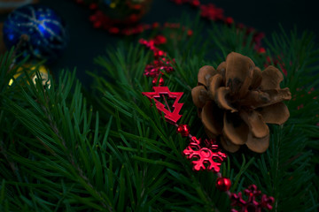 A cone on a Christmas tree with a red Christmas tree toy and other Christmas decorations on a concrete background