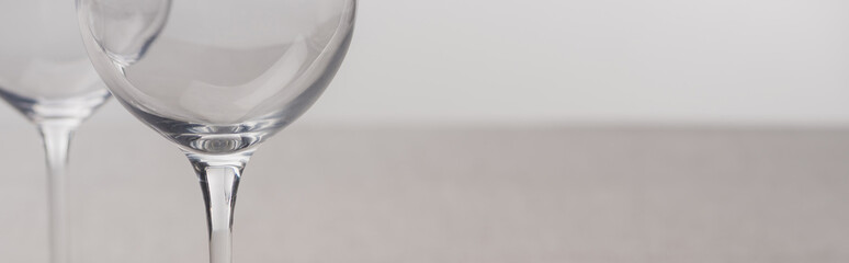 Panoramic shot of clear wine glasses isolated on grey