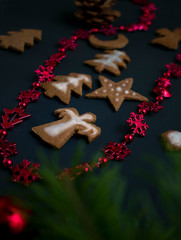 Christmas ginger cookies with white, sweet icing in the shape of Christmas trees, stars, angels and hearts on a dark concrete background with Christmas toys