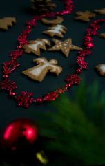 Christmas ginger cookies with white, sweet icing in the shape of Christmas trees, stars, angels and hearts on a dark concrete background with Christmas toys