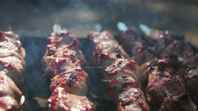 Close up barbecue meat roasting outdoor. Macro of smoked bbq grilling on brazier