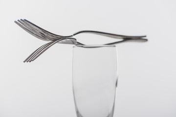 Selective focus of forks on clear champagne glass isolated on grey