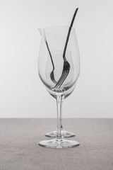 Selective focus of forks in clear wine glasses on tablecloth isolated on grey