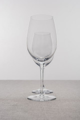 Selective focus of transparent wine glasses on tablecloth isolated on grey