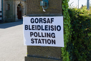 Obraz premium Polling station sign in Welsh and English language showing where people can go to cast their vote in an election in Wales UK