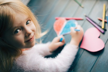 Handmade Valentine's day card. Little girl making valentine card. Girl making hearts. 14 february