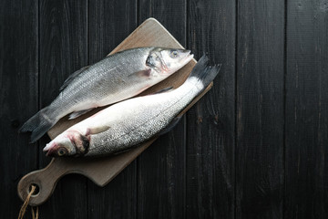 Fresh seabass . Raw fish seabass on black rustic table. Top view with copy space..