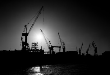 Obraz premium Hamburger Hafen Kran Kräne Container Terminal Elbe Deutschland Sonne Gegenlicht Silhouetten Technik Transport Verkehr Globalisierung Automatisierung Wirtschaft Übersee Kai Stimmung schwarz weiss