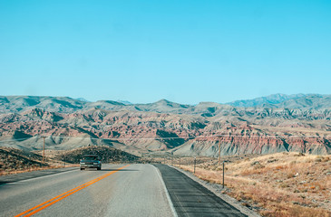 A wide road with red mountains in the background
