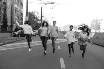 Multiracial group of friends runs and has a fun on city street.