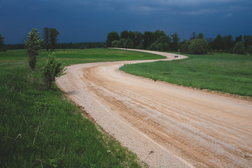 Winding dirt road in a field of Latvia