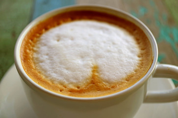 Closeup the texture of cappuccino coffee with milk foam on rustic wooden table