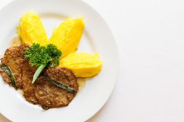 Delicious grilled burger served on a white plate with mashed potatoes aside. On a white background.