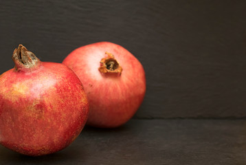 Ripe pomegranate on dark black background.