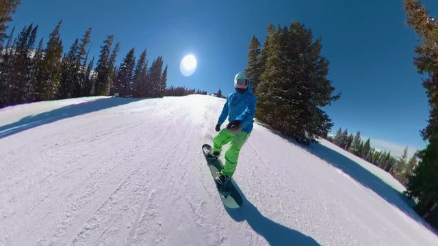 SELFIE: Cool snowboarder dude shreds the groomed slopes on a sunny winter day. Young man on active winter vacation snowboards around a beautiful ski resort on Copper Mountain. Awesome winter sport.