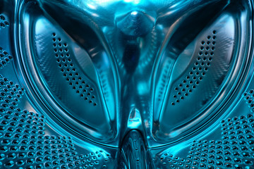Futuristic look of a washing machine drum made of steel in blue light