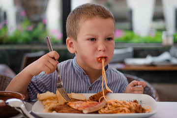 6 year old boy of European appearance eats spaghetti pasta