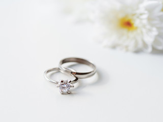 Wedding and engagement rings with diamond with white chamomile flower. Symbol of love and marriage on white background.
