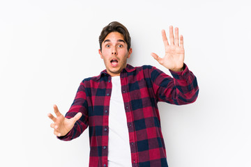 Young caucasian man posing in a pink background isolated being shocked due to an imminent danger