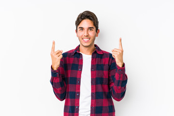 Young caucasian man posing in a pink background isolated indicates with both fore fingers up showing a blank space.