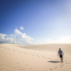 Fototapeta na wymiar A solitary man making his way through the hot sun and sand dunes of Maranhao, Brazil.