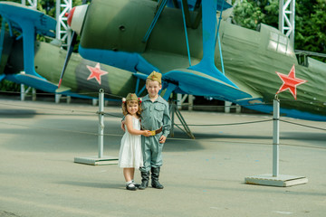 a boy of European appearance 6 years old in military uniform and a cute girl 4 years old in a white sundress, a reenactment of a meeting of a soldier with a bride, the theme of the great Patriotic war