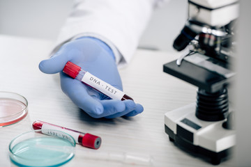 Fototapeta premium cropped view of genetic consultant holding test tube with dna test
