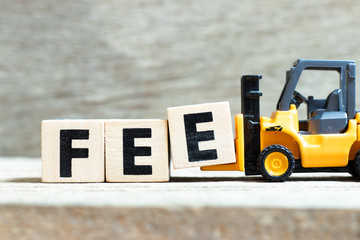 Toy forklift hold letter block e to complete word fee on wood background