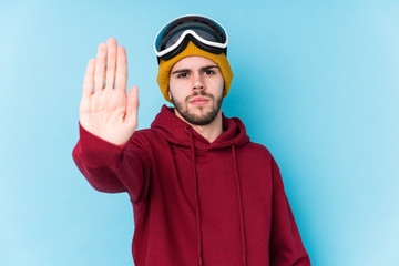 Young caucasian man wearing a ski clothes isolated standing with outstretched hand showing stop sign, preventing you.