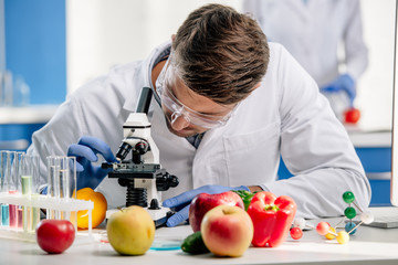 molecular nutritionist in white coat using microscope in lab