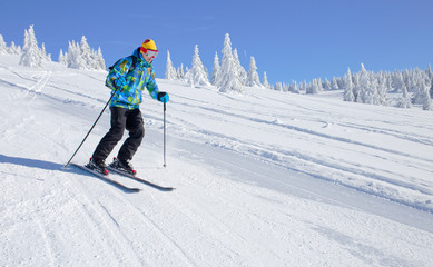 Fototapeta na wymiar Active Skier skiing downhill on ski piste in mountains 