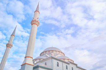 Fototapeta na wymiar Minarets of a mosque opposite cloudy blue sky