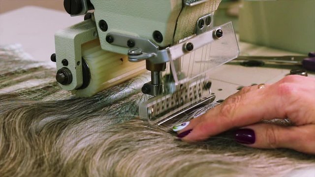Wig manufacturing process, woman collects a wig. Wig assembly close-up