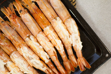 big prawns, seafood, vitamins. the process of cooking shrimp. the concept of cooking and healthy eating. a lot of fresh crayfish are lying on a plate, top view. seafood dish. tiger prawns with garlic