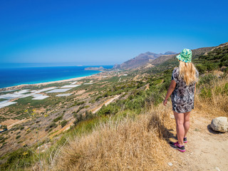 Crete, Greece: Blonde pretty girl enjoying beautiful views of Falassarna beach on the northwest of Chania prefecture, one of the best 100 beaches of the world