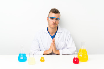 Young scientific with lots of laboratory flask pleading