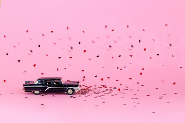 Ulianovsk. Russia. January 9, 2020. Toy car and hearts. Miniature copy on a pink background. Idea for Valentine's day and wedding greeting cards. Empty space for text