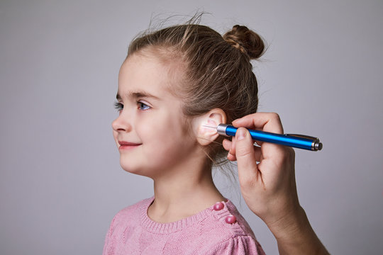 Doctor Examining Girl's Ear With Medical Flashlight Pen. Audiologist Examining Little Patient With ENT Flashlight, Hearing Exam Of Child