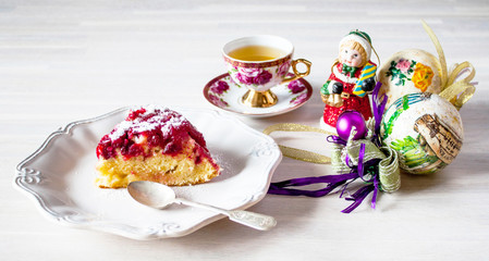Obraz na płótnie Canvas Piece round cranberry tart pie cake, white plate, tea cup on wooden table with christmas decoration