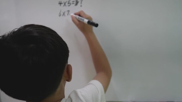Unrecognizable kid is struggling with math equation which is written on the board