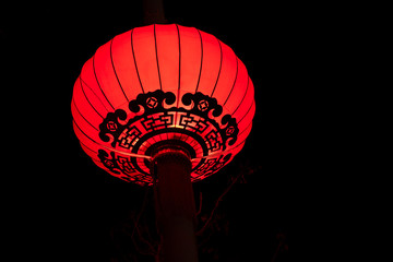 Chinese red lantern on a pillar against the background of the night sky.