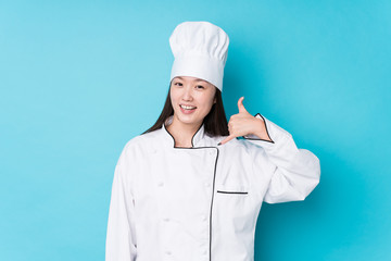Young chinese chef woman isolated showing a mobile phone call gesture with fingers.