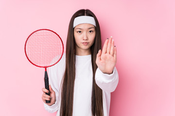 Young chinese woman playing badminton isolated standing with outstretched hand showing stop sign, preventing you.