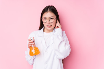 Young chinese scientific woman isolated covering ears with hands.