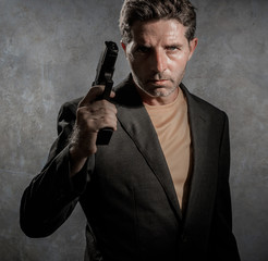 grunge cinematic portrait of attractive and dangerous looking mafia hitman or secret service especial agent man in blazer pointing gun in crime mob and criminal lifestyle concept - obrazy, fototapety, plakaty
