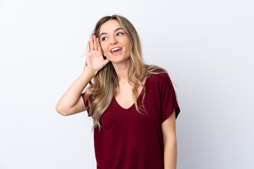 Young woman over isolated white background listening to something by putting hand on the ear