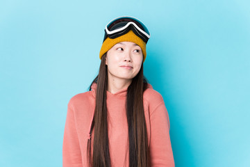 Young chinese woman wearing ski clothes isolated dreaming of achieving goals and purposes